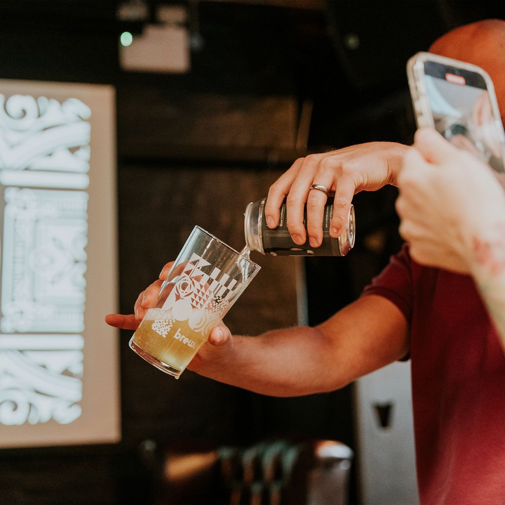 A drink being poured into a brew branded pint glass.