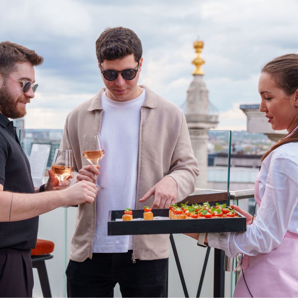 Guests drinking wine and choosing from a selection of canapes.