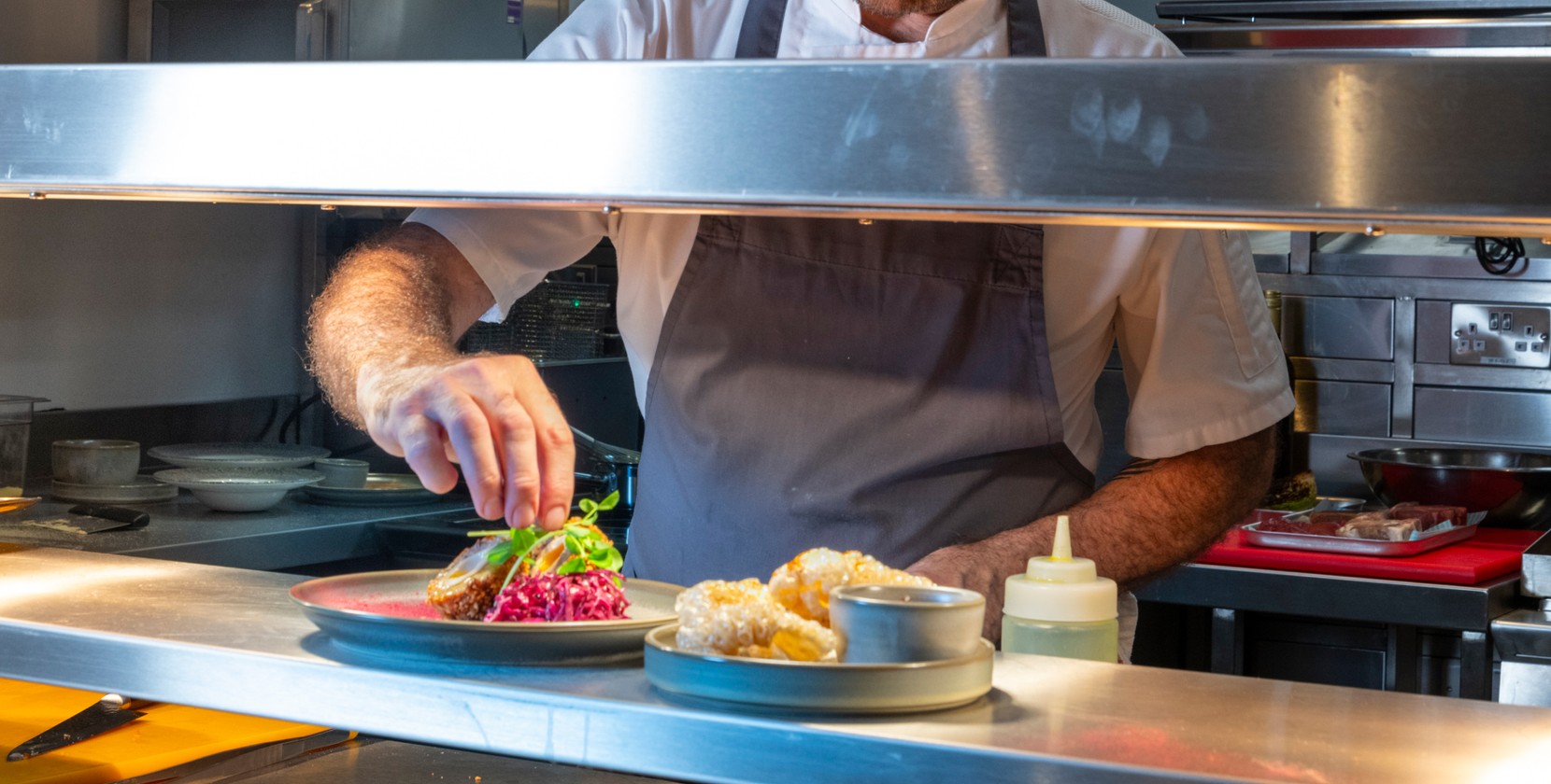 A dish being finished with watercress by the chef. 