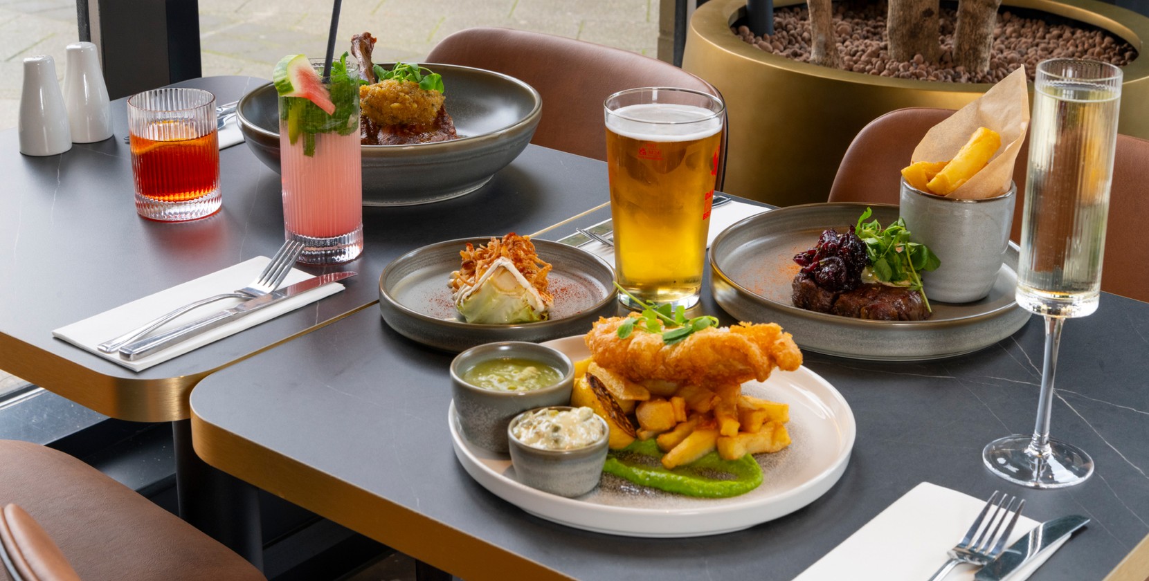 A shot of a bright, airy table with pub classics and drinks waiting. 