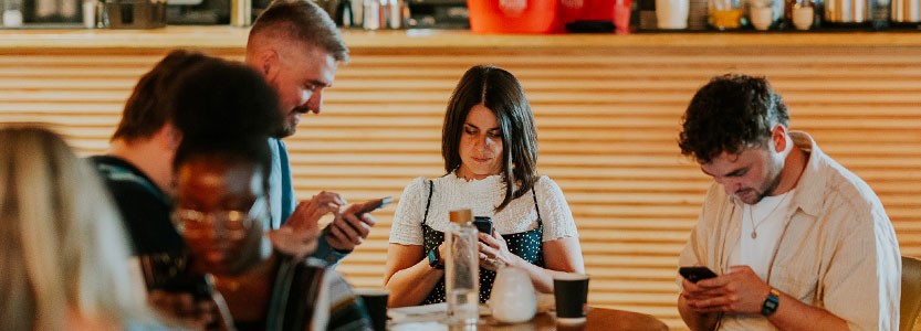 People sitting at a table using mobile phones during a social media session.