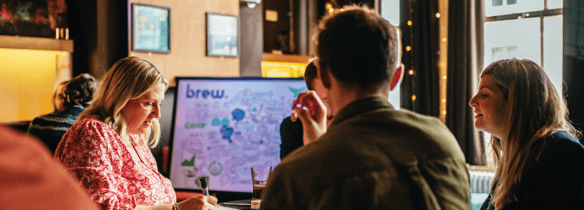 A photograph of the Brew marketing team brainstorming local marketing ideas around a table.