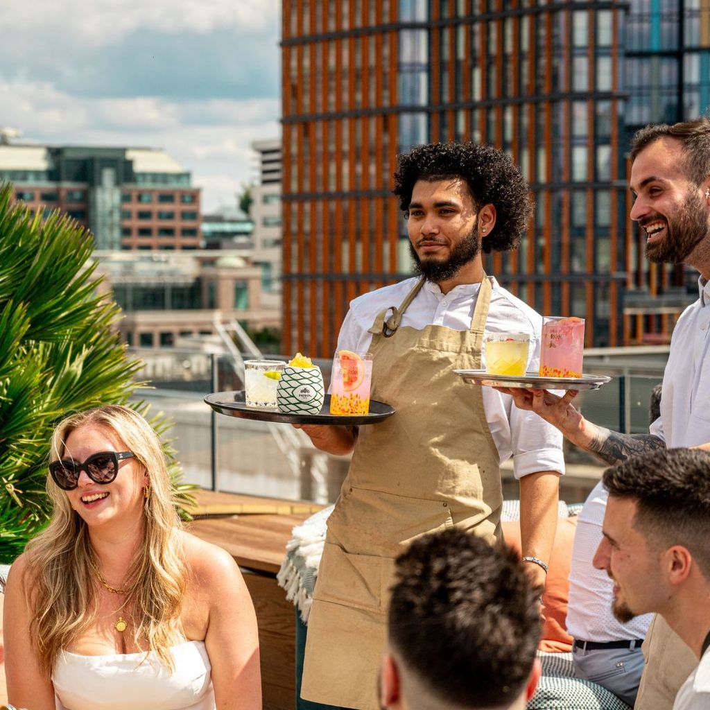 Bar staff serving cocktails to guests on a stylish terrace.