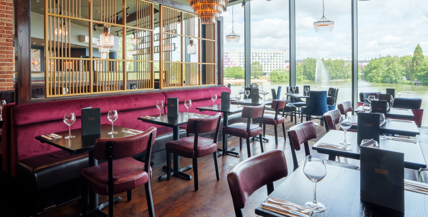 A bright, airy dining room with freshly laid tables. In the background, spacious green views.