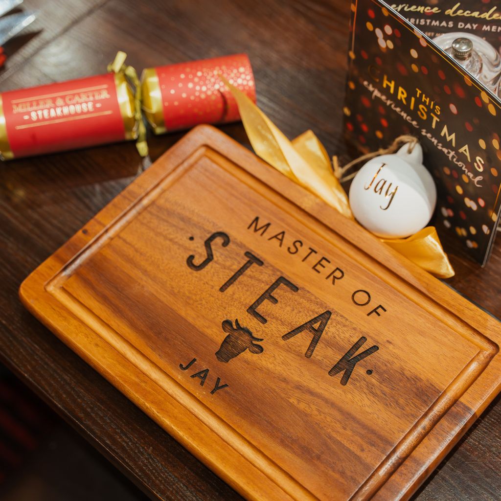 A personalised wooden steak board on a festive dinner table.