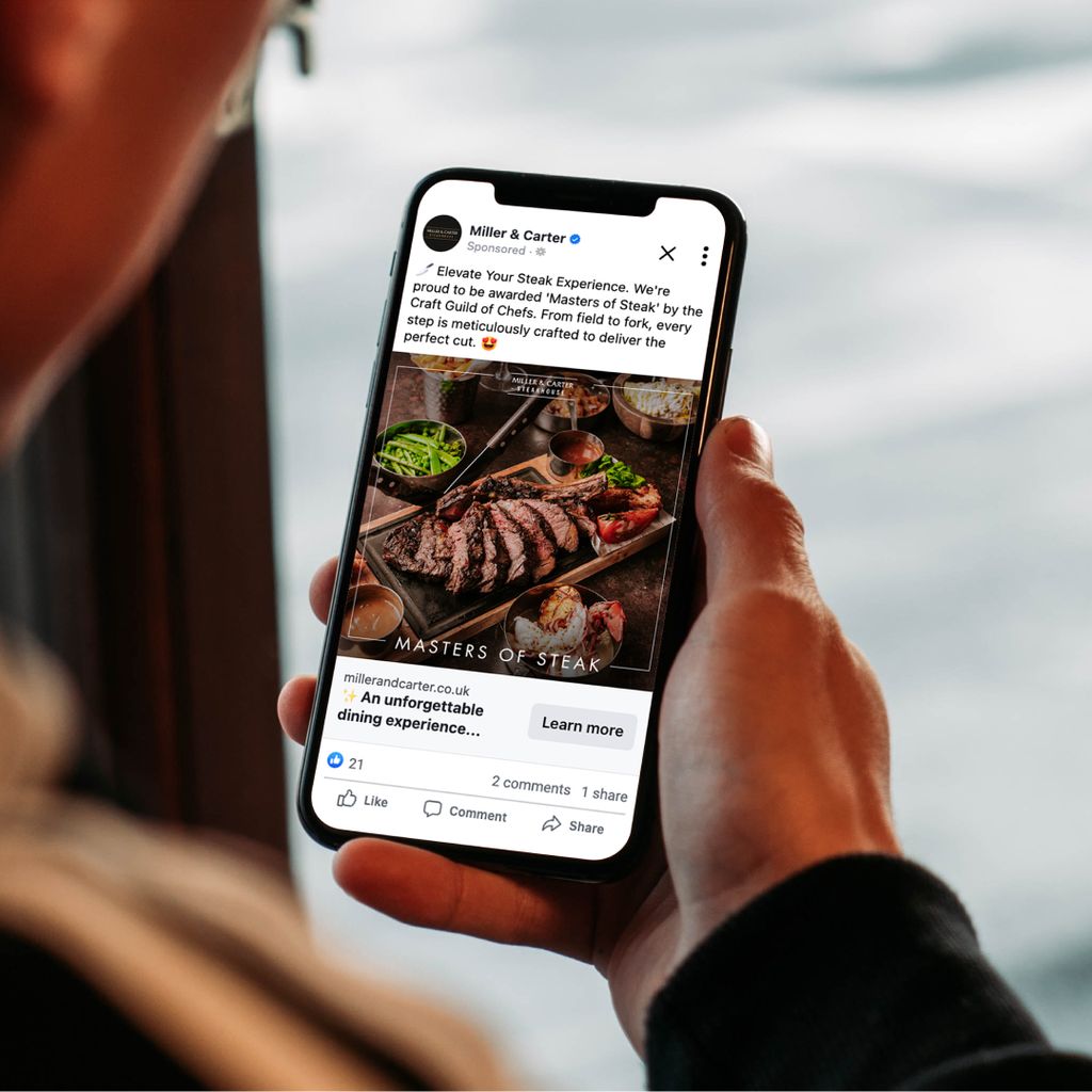 Someone holding an iPhone displaying a Miller &amp; Carter social post about steaks. 