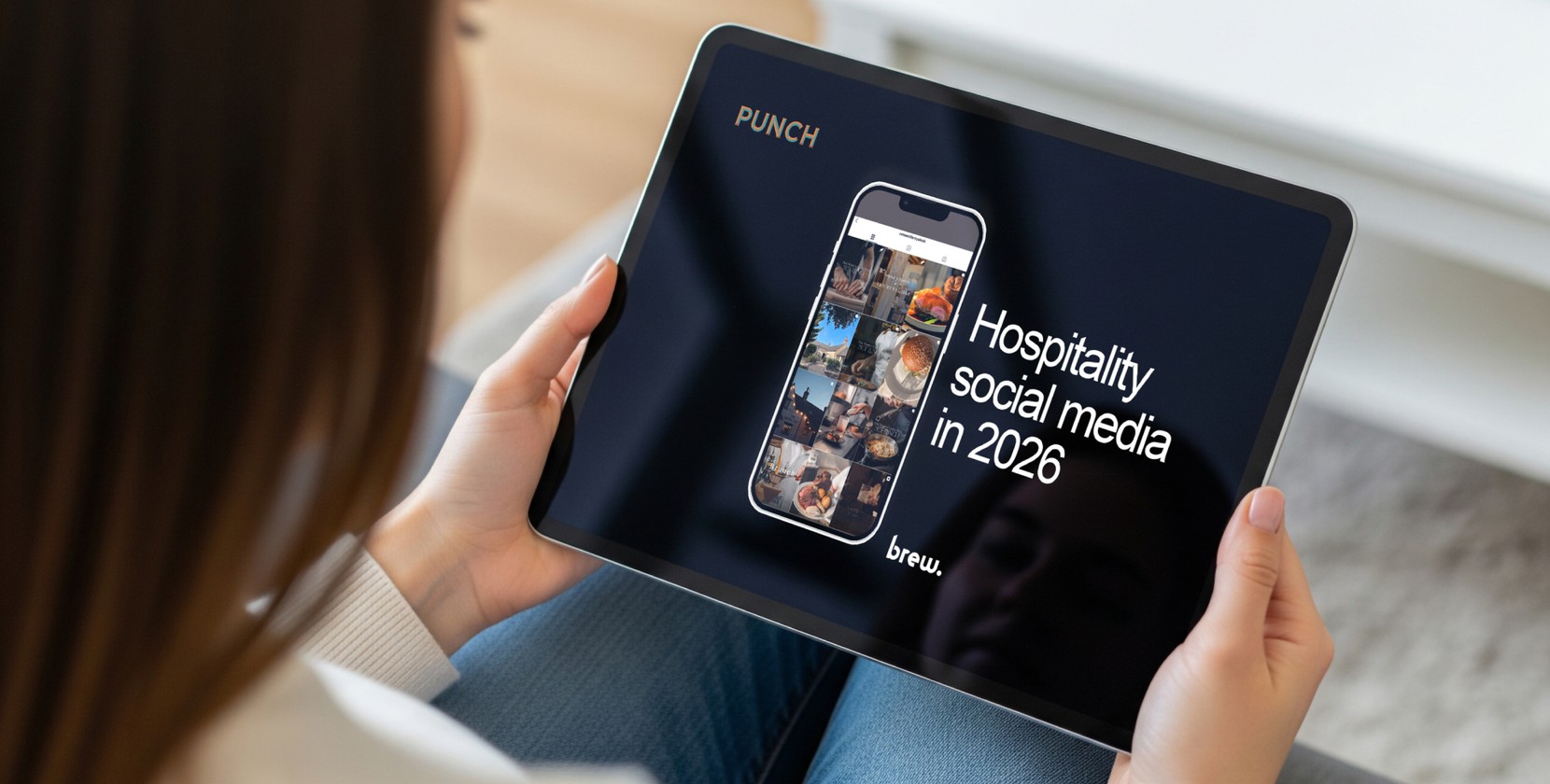 A photo of a seated person holding a tablet in their lap. The tablet displays the front cover of a social media training for pubs guide, which reads “Hospitality social media in 2026”. 