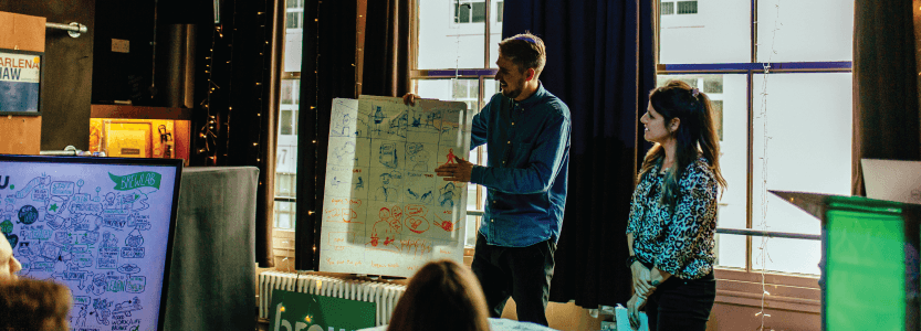 2 digital marketeers deliver social media training to a room of workshop attendees.