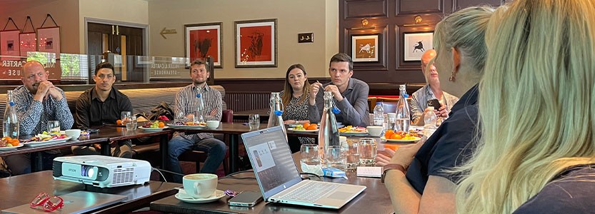 Group of people seated around a meeting table during a training presentation.