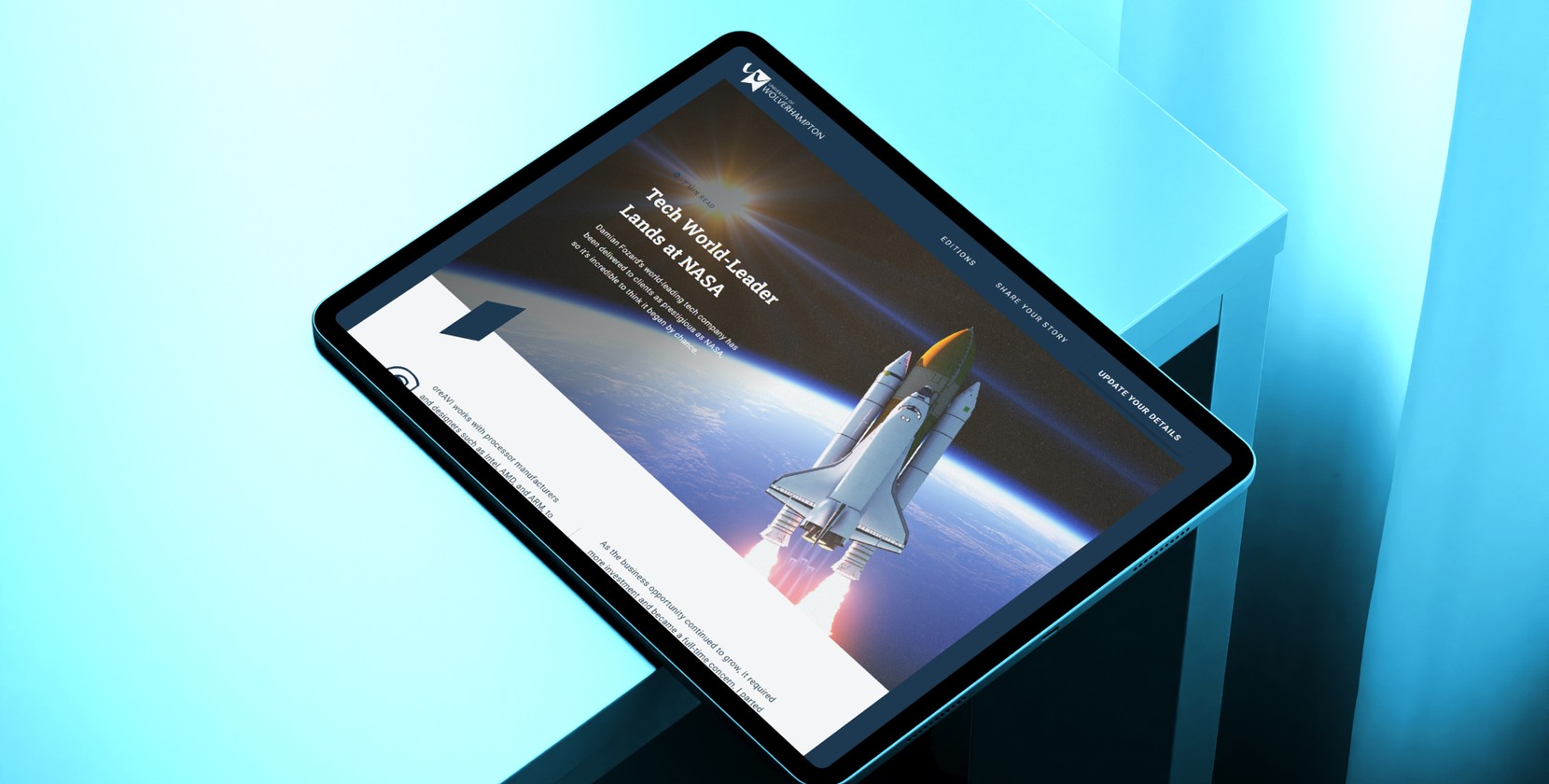 A blue table with a large tablet device sitting over the edge. The tablet screen displays an article from the online alum magazine of the University of Wolverhampton (WLV Life).