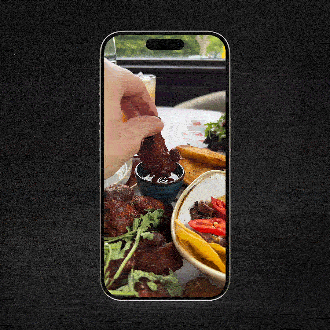 A wing being dunked into shiny BBQ sauce.