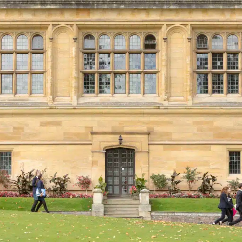 Students walking past the grand windows and stone walls of Malvern College.