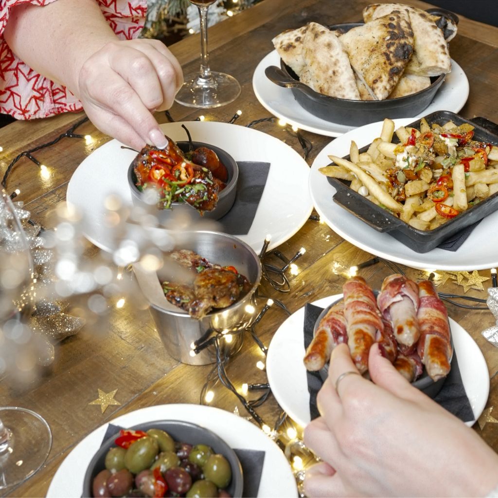Diners picking up pigs and blankets and festive starters.