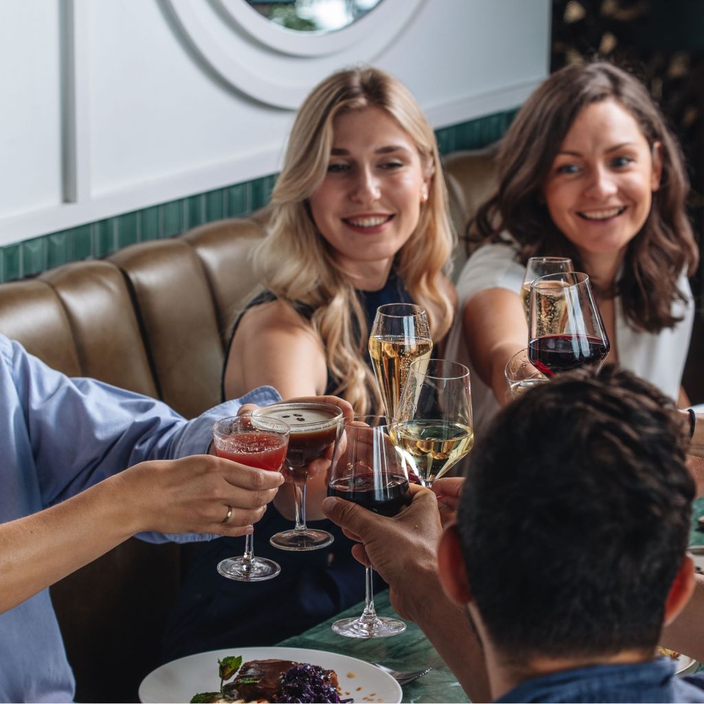 A group of friends clinking glasses at their table.