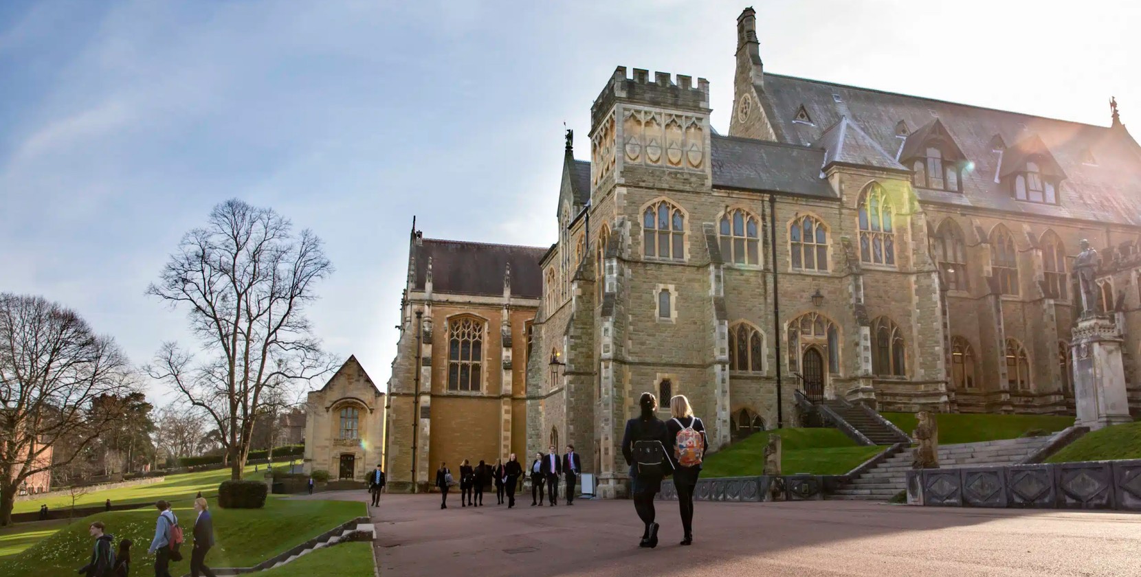 Part of a Malvern College stone building with students milling around in the foreground.